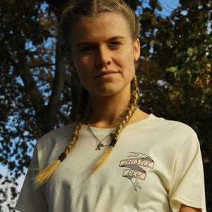 Person wearing a white t-shirt with a logo in an outdoor setting