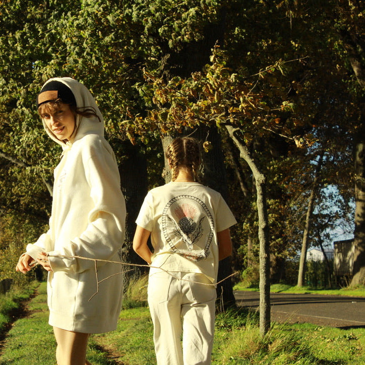 Three people standing outdoors with trees and a path in the background